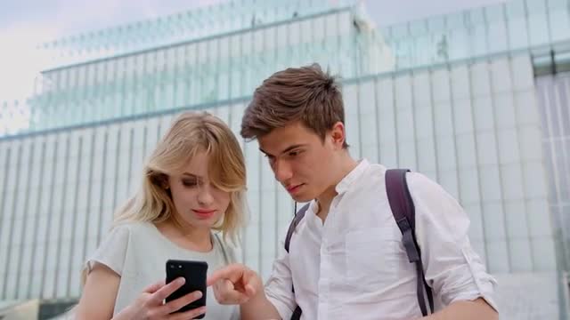 A Young Couple Using a Mobile Phone Outdoors