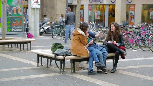 Young girl student fooling around and laughing while sitting on a bench