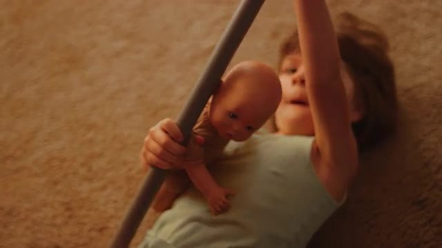 A little girl playing on the carpet with a toy horse and baby doll