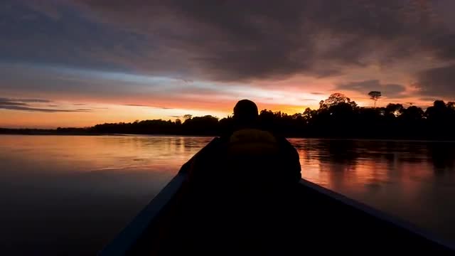 Epic sunrise over river landscape from boat, silhouette of captain present, 4k