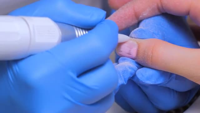 The master uses an electric machine to remove the nail polish