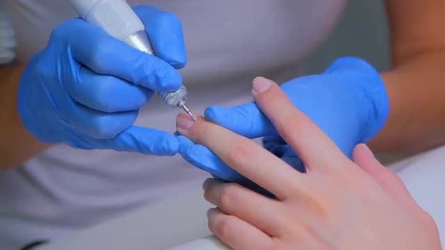 Master of manicure with special device removes the cuticle