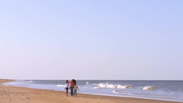 Mother and daughters strolling on beach