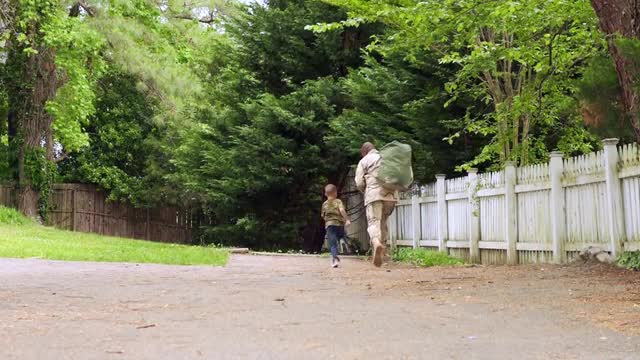 African American military father running on path with son