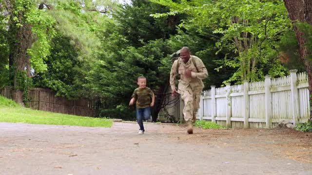 African American military father running on path with son
