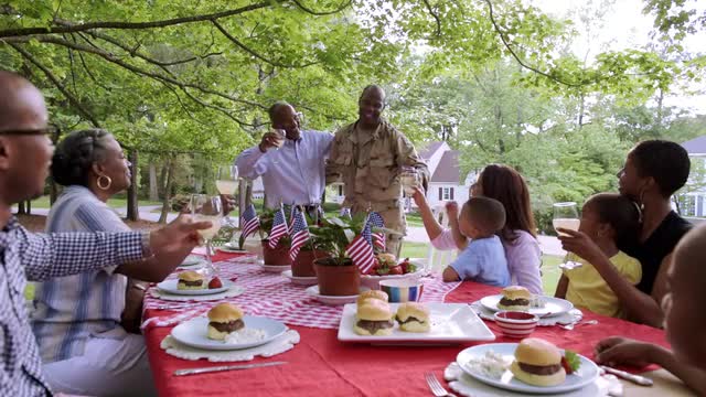 Extended family toasting military man at picnic