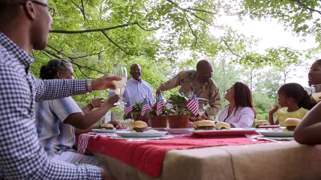 Extended family toasting military man at picnic