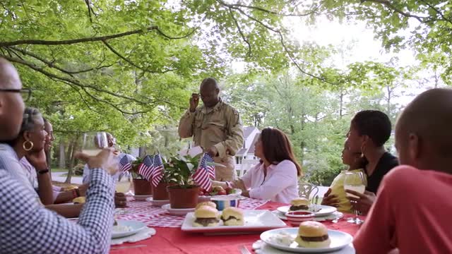 Extended family listening to military man reading letter at picnic