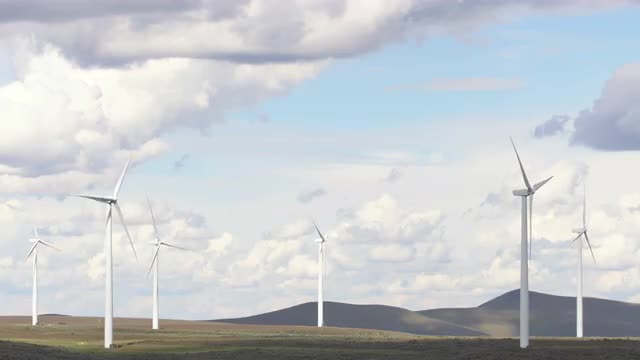 Wind mills spinning across grassy plains