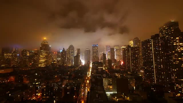 clouds moving over city skyline at night sky. urban building lights background