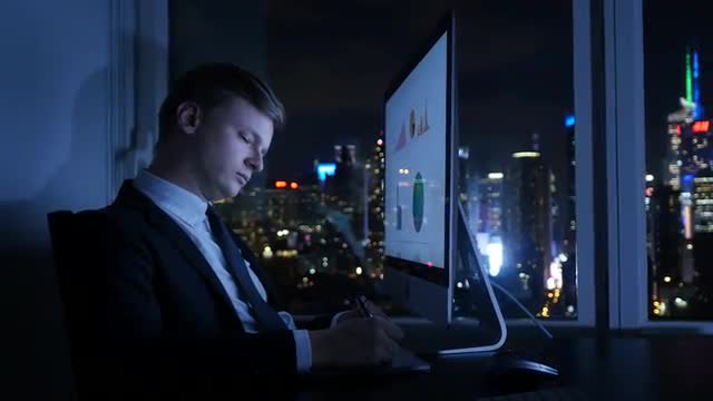 young caucasian businessman working in modern office. city skyline background