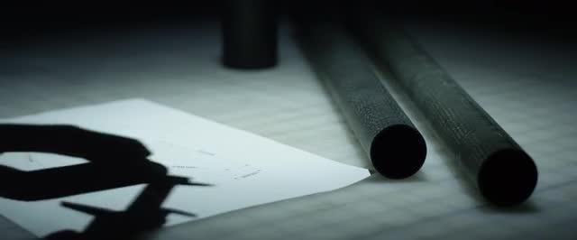 Static Close Up of man measuring carbon fiber tubes on a workbench.