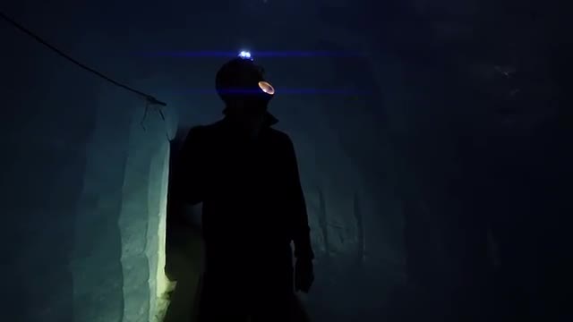 flashlight beaming light. silhouette of person. dark cave. cold ice