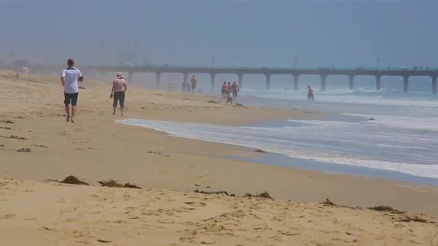 People walk on the Manhattan Beach in California
