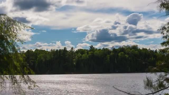 Time lapse of clouds above a lake framed by trees