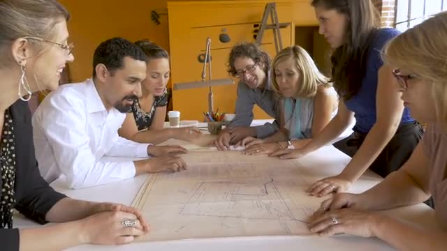 Female manager reveals blueprints to her fellow startup coworkers in slow motion
