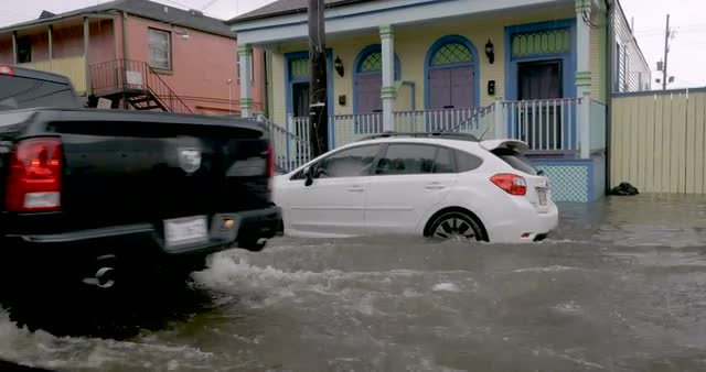 Truck driving by amongst flooded streets and cars in flood waters in NOLA