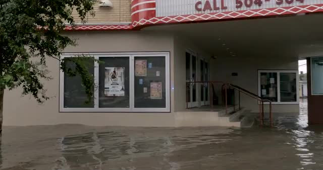 POV driving by a flooded theater caused by climate change in New Orleans