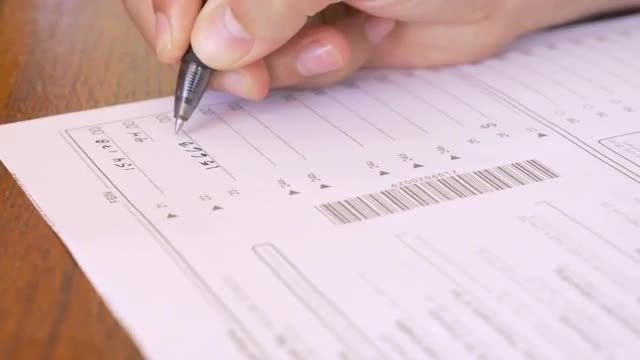 Hand writing numbers on paper tax form with a pen in 4k dolly close up