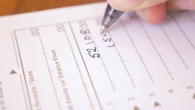 Close up of hand filling out a tax form with a black ink pen- push in dolly