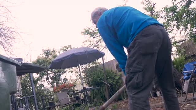 Hand held of an older senior using a shovel to clean up his yard