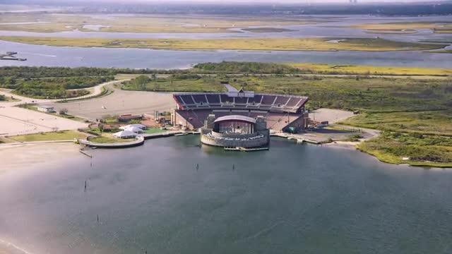 LONG WIDE AERIAL POV toward and over light traffic on Ocean Parkway and Nikon at Jones Beach Theater