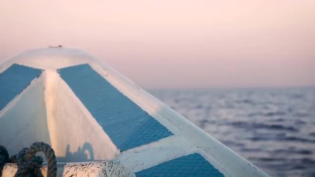 Handheld of the bow of a small boat bouncing on calm water during sunrise