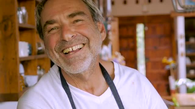 A smiling happy baby boomer man looks at the camera with a minor diastema