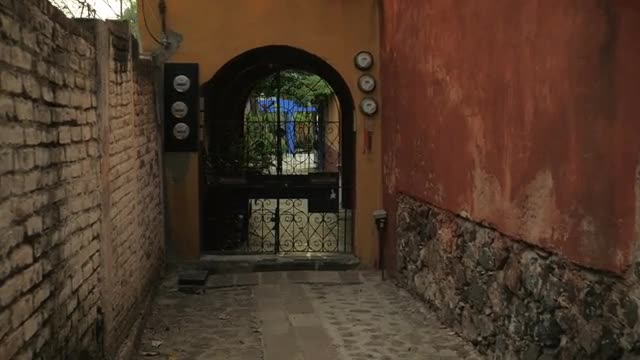 Camera approaches a closed iron gate in an alley in a historic town in slow mo