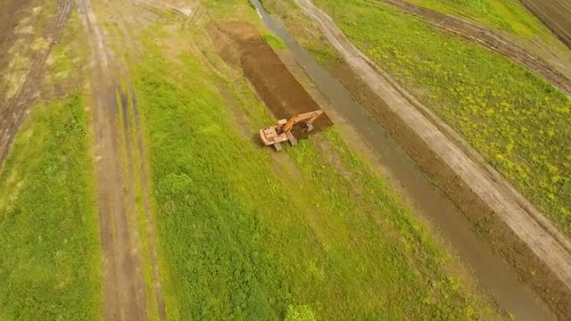 Excavator digging a trench in the field.Aerial video.