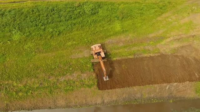 Excavator digging a trench in the field.Aerial video.
