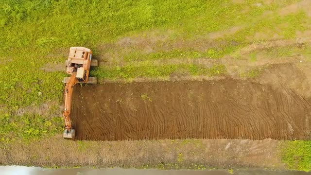 Excavator digging a trench in the field.Aerial video.
