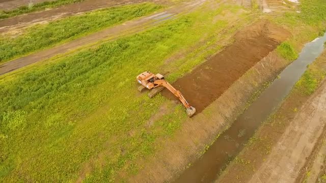 Excavator digging a trench in the field.Aerial video.