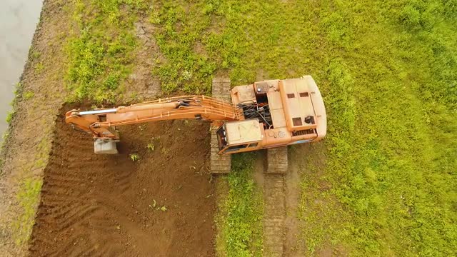 Excavator digging a trench in the field.Aerial video.
