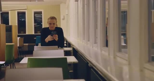 Woman spending evening sitting alone in cafe and using cellphone