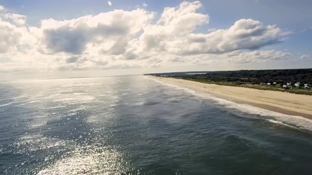 WIDE AERIAL POV along beach on Atlantic Ocean