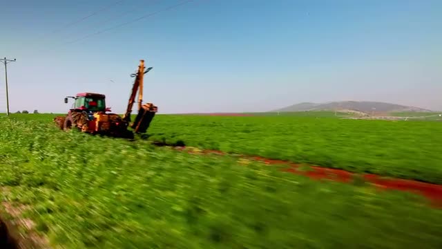 Stock Video Footage drive-by of a tractor and a green field in Israel.