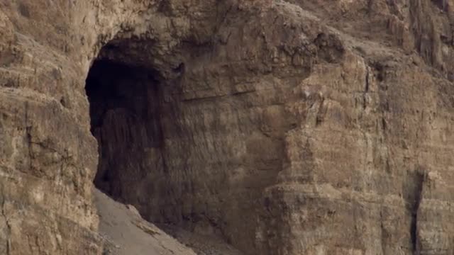 Panning shot of A cave in a cliff face shot in Israel.