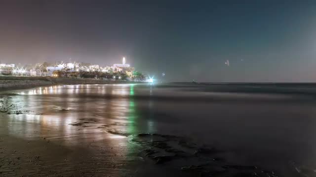Panning shot of Moon setting into the ocean near an Israeli city