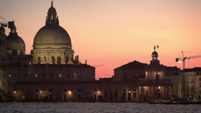 Static shot of Santa Maria della Salute and boats in the canal at sunset.