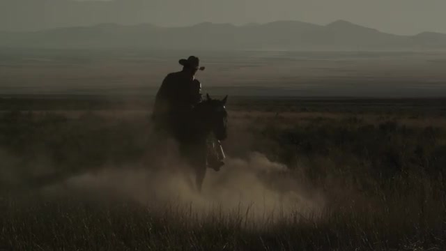 Slow motion static shot of cowboy riding a horse that is turning around