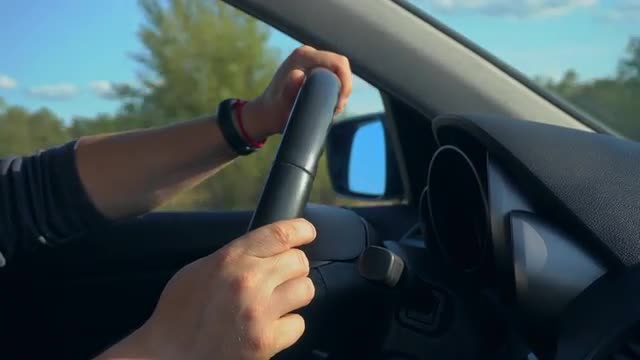 Inside a Car. A Man's Hands on the Steering Wheel