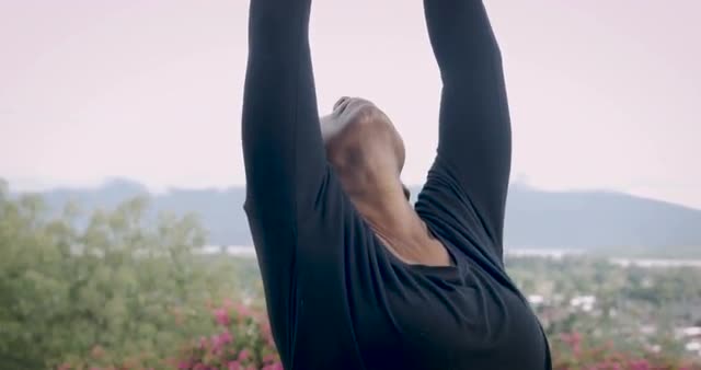 Fit athletic senior woman stretching her spine outdoors with yoga