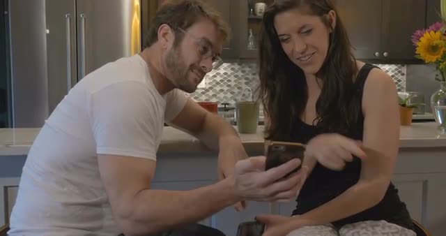 Attractive couple looking at the same smart phone together laughing and smiling
