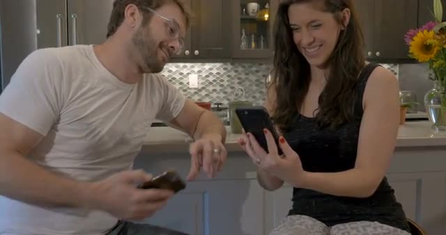Gorgeous woman laughing with an attractive man looking at a cell phone together