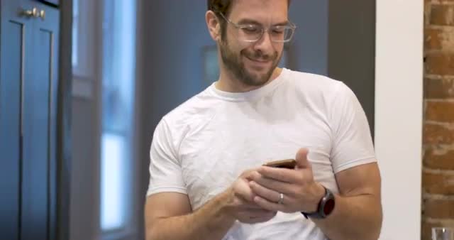 Dancing young man using mobile phone pumping arm in air celebrating success