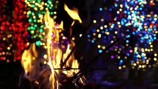 Fire burning with Christmas lights in the background