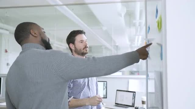 Businessmen brainstorming at wall in startup office