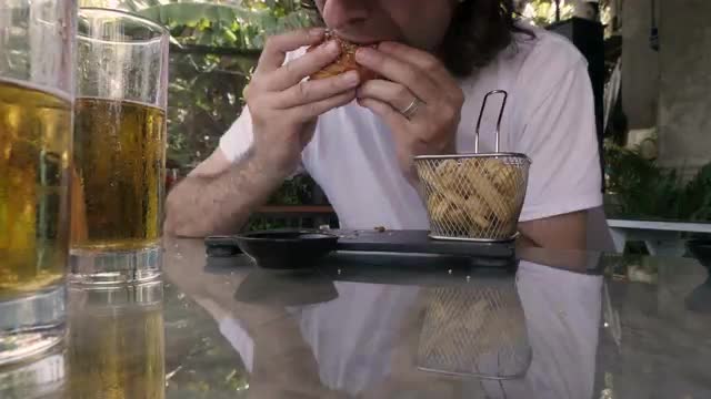 Time lapse of a man eating a hamburger and french fries and drinking beer