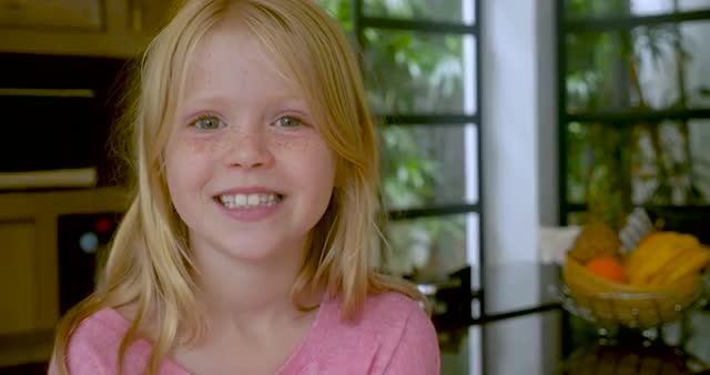 Blond haired little girl with freckles smiling and looking at camera